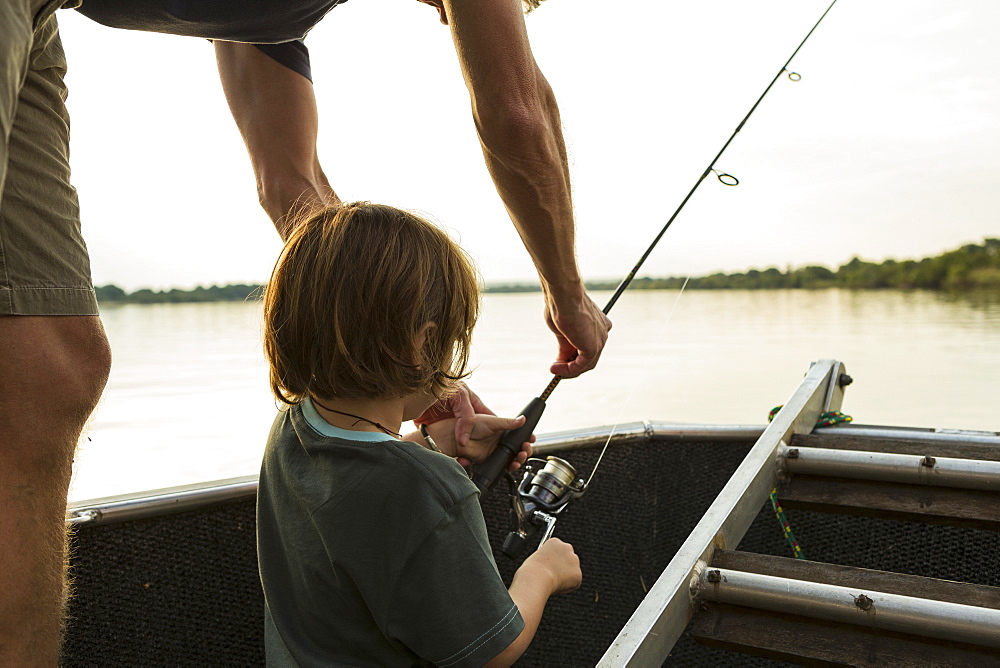 A five year old boy fishing from a boat on the Zambezi River, Botswana, Zambezi River, Botswana