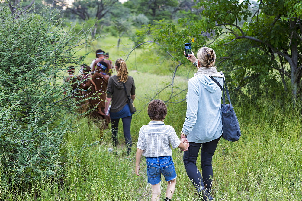 A boy and his mother, tourists on a walking trail following members of the San people, bushmen