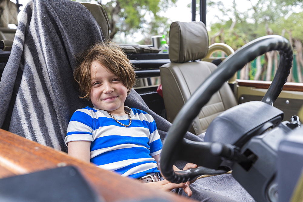 Smiling Six year old boy in the driver's seat of a safari vehicle in Botswana