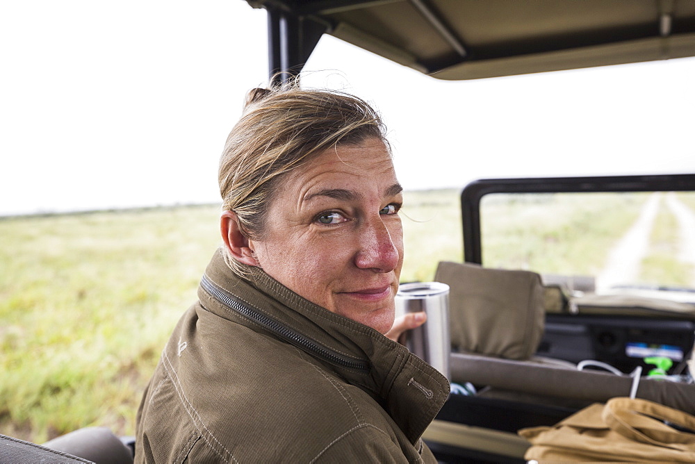 Portrait of adult woman in the front seat of a safari vehicle looking over her shoulder