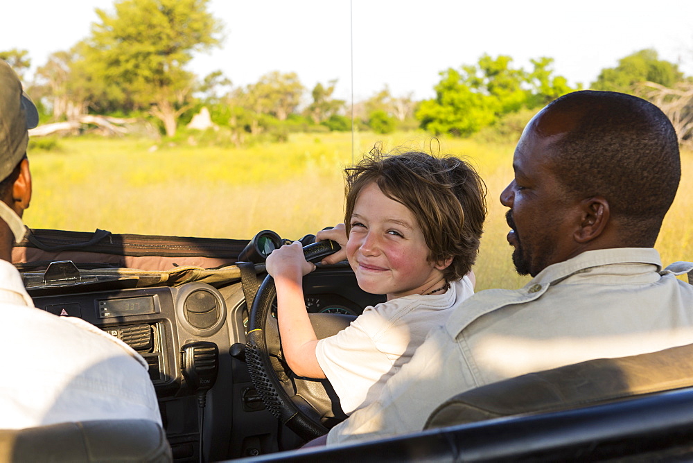 smiling Six year old boy steering safari vehicle, Botswana