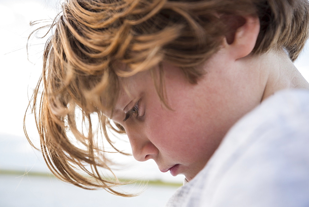 Close up profile of a Six year old boy looking down, head and shoulders