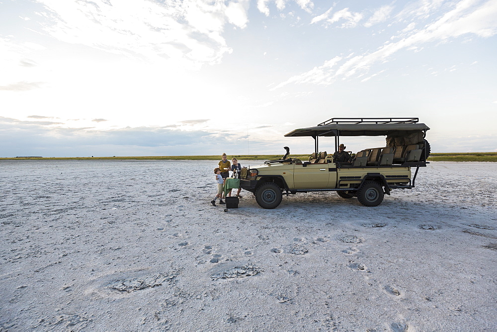 A safari vehicle parked in the salt pans landscape at dusk, Makgadikgadi Pan National Park, Botswana