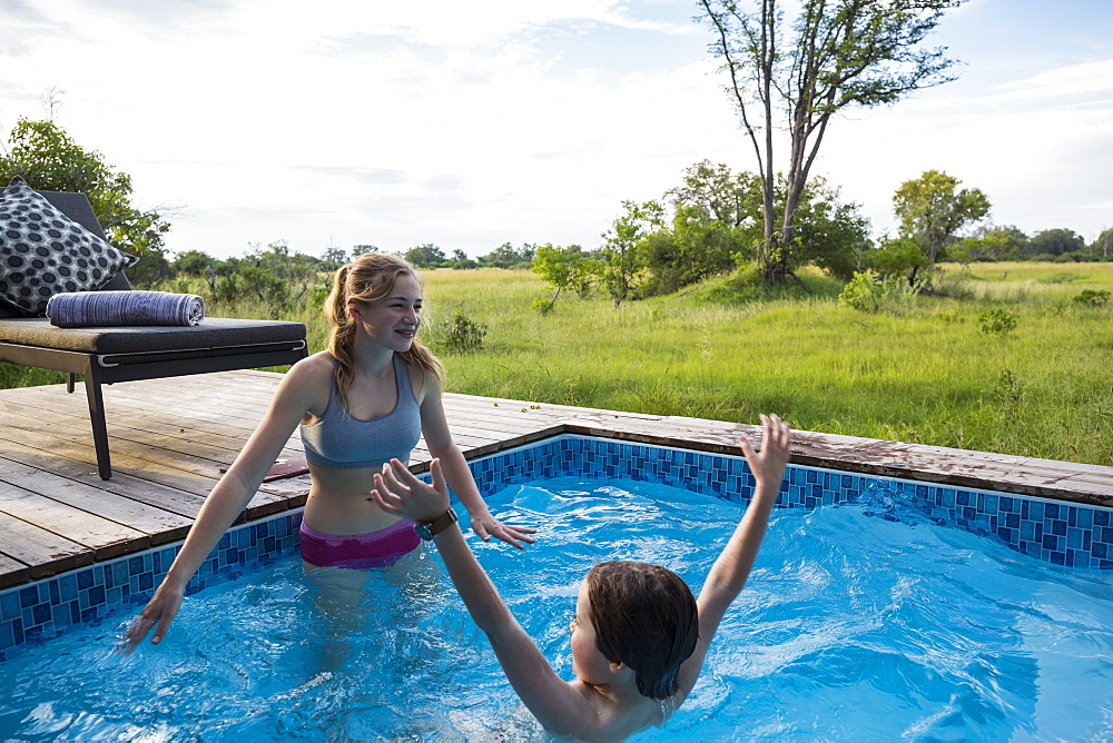 Brother and sister, Two children swimming in small pool at a safari camp, Botswana