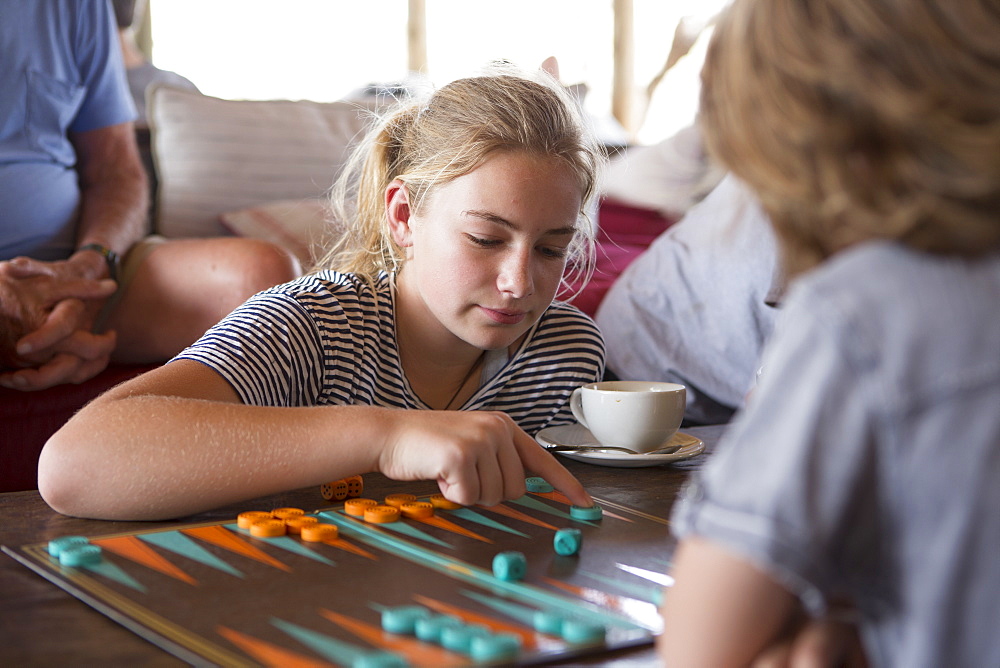 A family on vacation, people playing backgammon at a tented camp in a wildlife reserve, Okavango Delta, Botswana