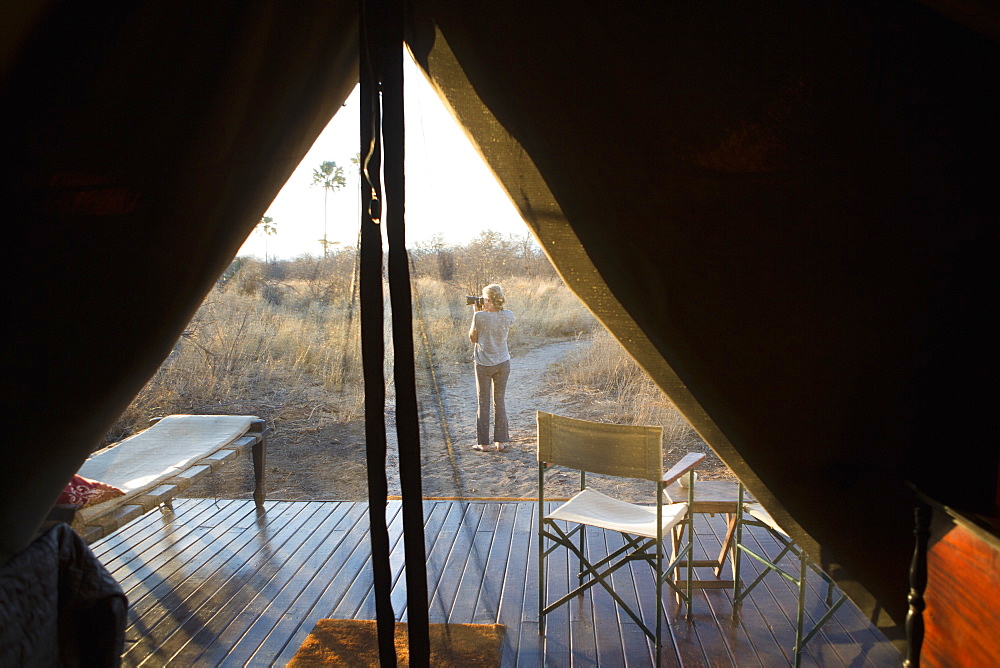 Woman taking a photograph at dusk, in the Kalahari Desert