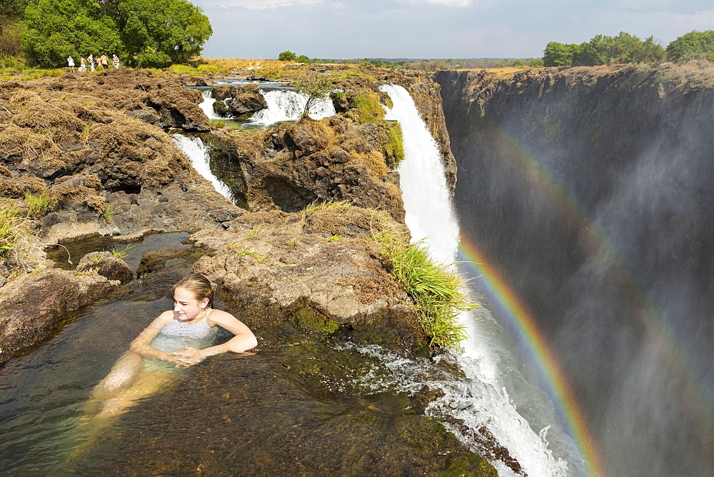 Young teenage girl in the water at the Devils Pool, on the cliff top overlooking Victoria Falls, Zambia, view from above