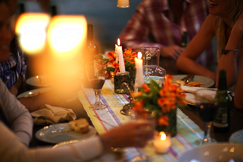 People sitting at a table with wine glasses, plates, flowers and candles