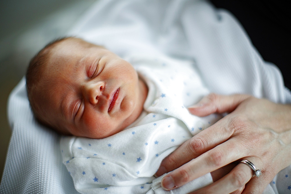 Sleeping baby with mother's hand resting on his chest