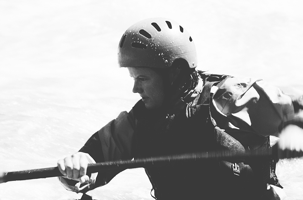 Female whitewater kayaker paddling rapids and surf on a fast flowing river