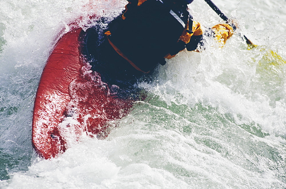 Female whitewater kayaker paddling rapids and surf on a fast flowing river