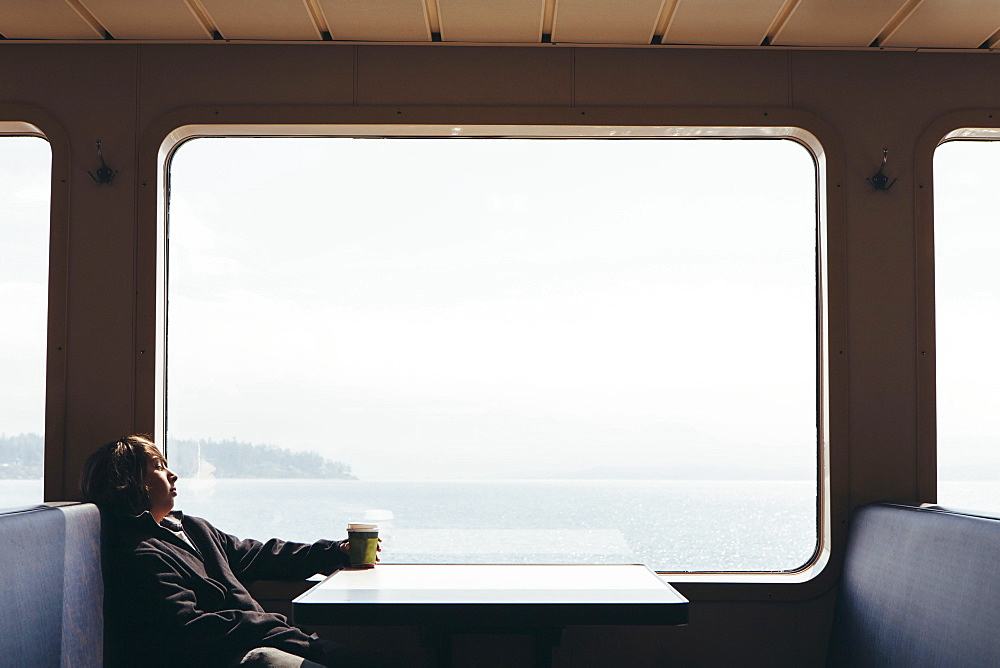 Teenage boy sitting on ferry looking out of a window