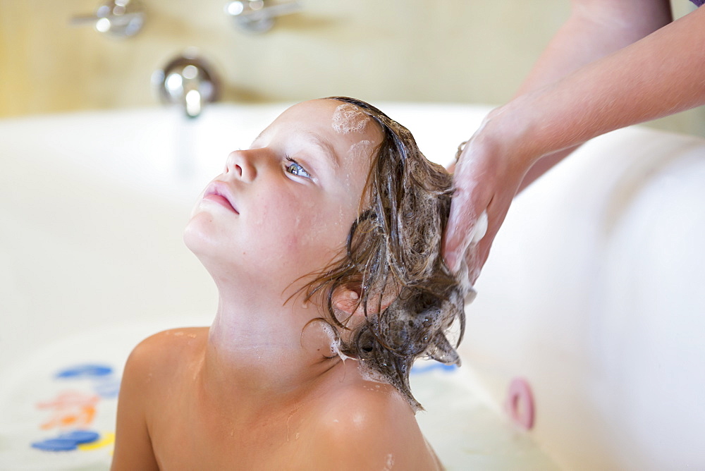 4 year old boy having a bath and shampoo in bath tub