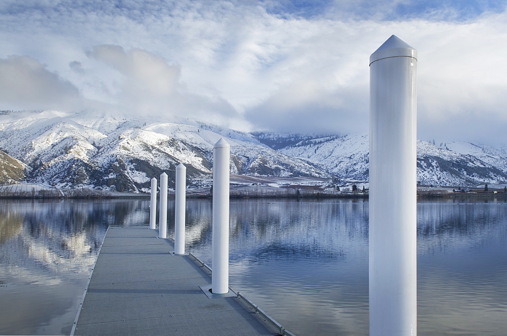 Pillars on dock at lake near snow covered mountain range, Washington, United States