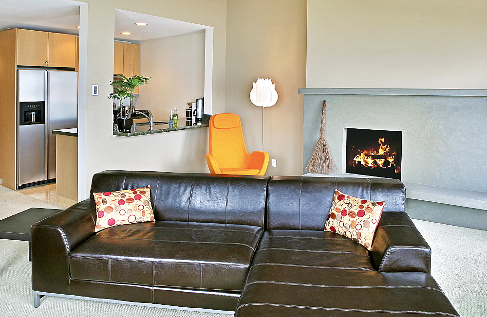 Open plan living room and kitchen in a modern home, a lit fire and sectional sofa, Washington, United States