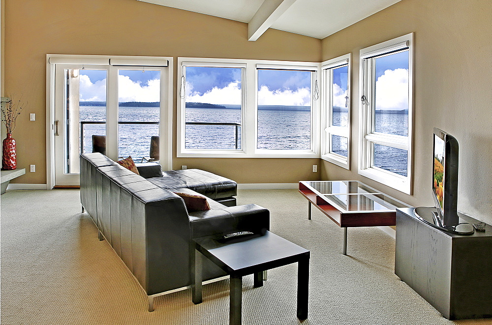 A living room in a waterfront house, with a large window and an ocean view, Washington, United States