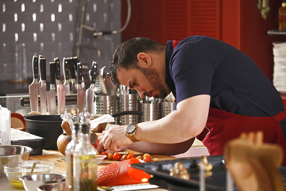 A chef bending and preparing food in a commercial kitchen, Russia