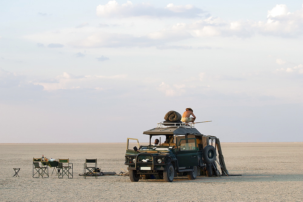 Man standing on top of 4x4 parked on the Makadikadi Salt Pans in Botswana