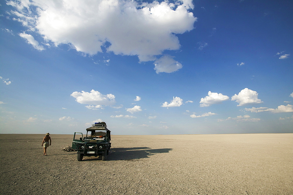Man walking past 4x4 parked on the Makadikadi Salt Pans in Botswana