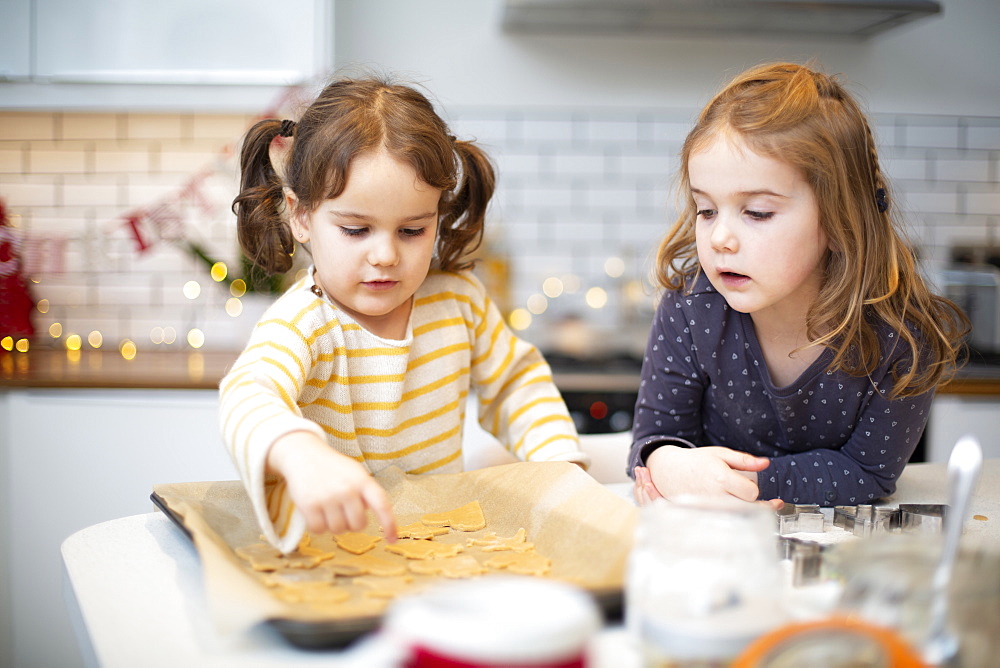 Two girls standing in kitchen, baking Christmas cookies