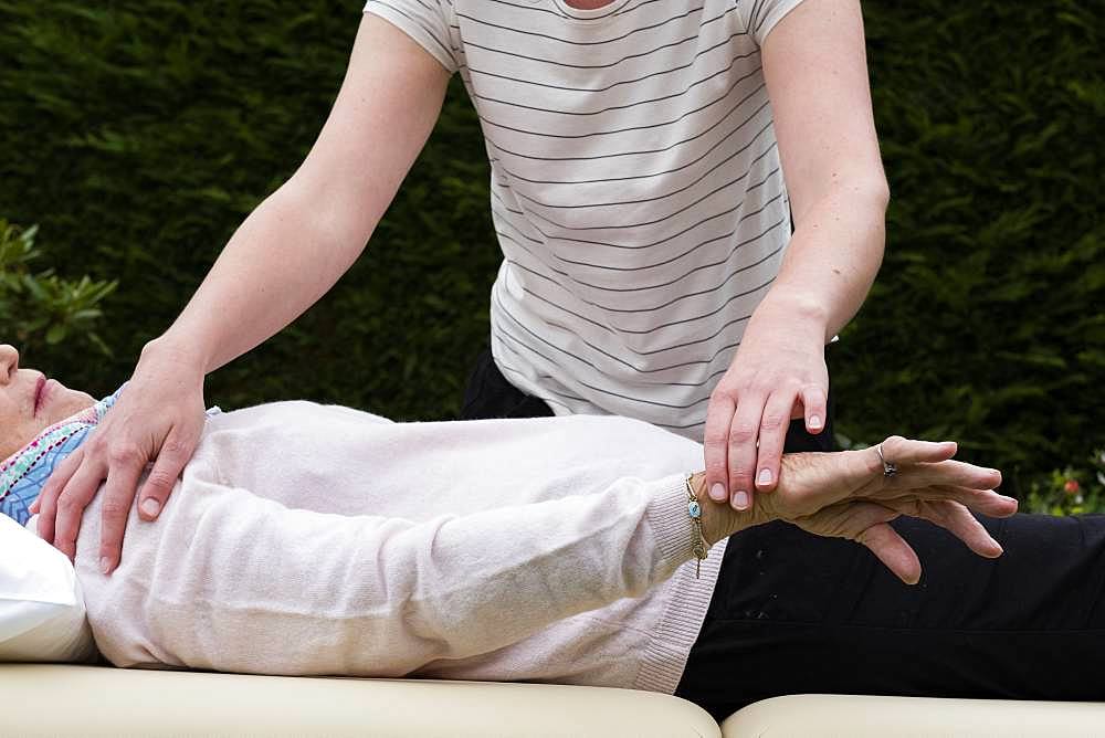 Reiki therapist with a client in a therapy session touching meridian points on the body