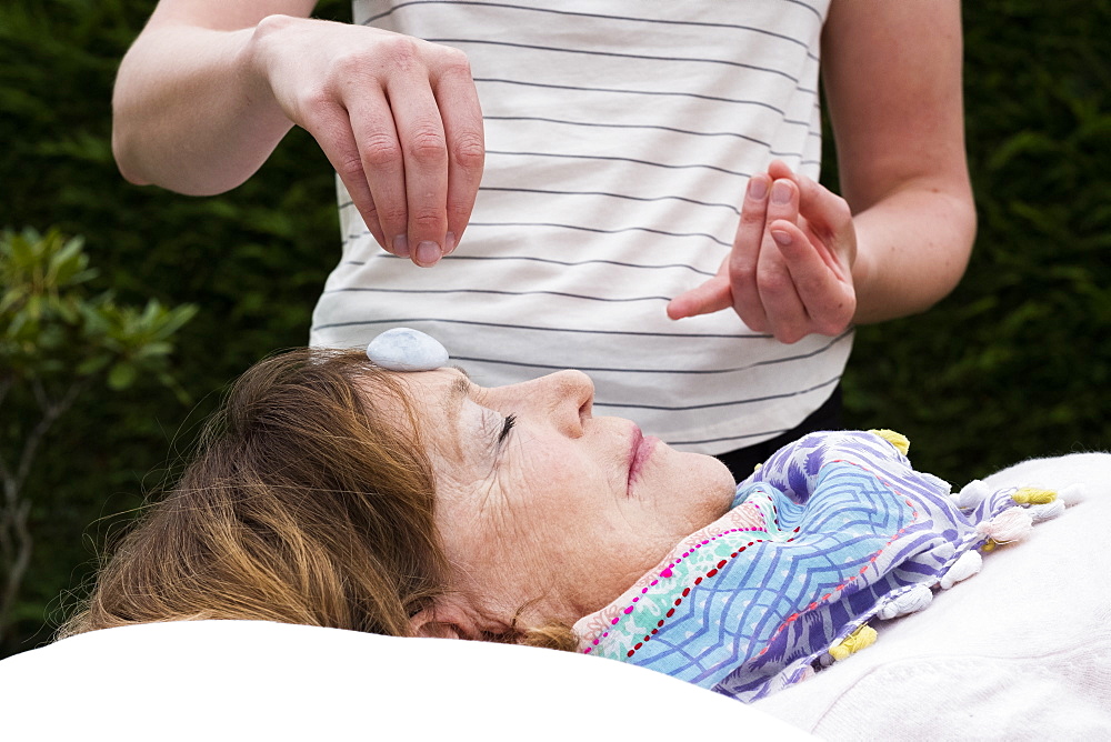 Reiki therapist with a client in a therapy session touching meridian points on the body