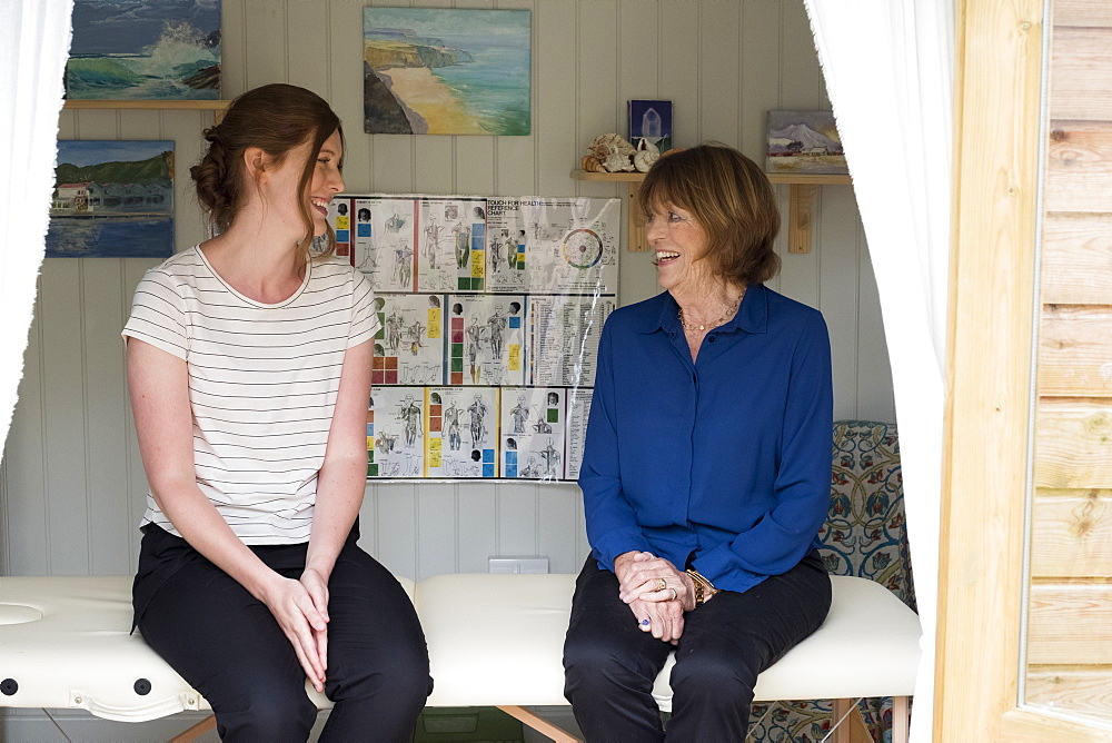 Woman and female therapist talking seated on a treatment couch