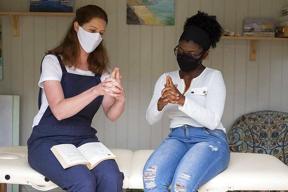 Woman and female therapist in face masks, hands steepled, EFT therapy