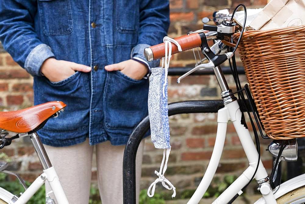 Close up of woman standing next to bicycle, face mask hanging from handlebar, Oxfordshire, England, United Kingdom