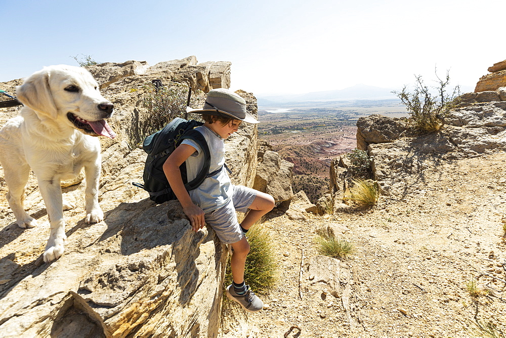 young boy hiking with his dog on Chimney Rock trail, through a protected canyon landscape, New Mexico, United States of America