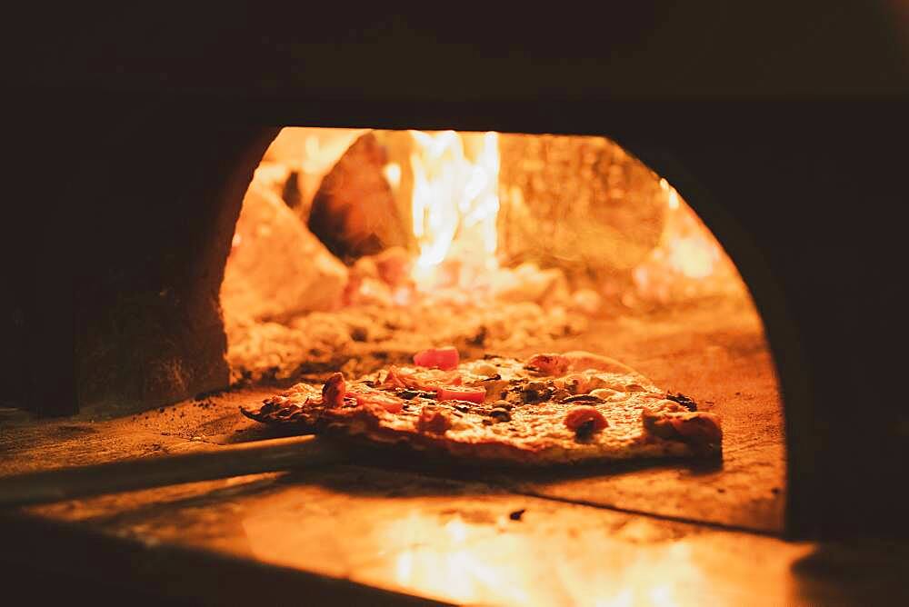 Close up of pizza in a wood-fired oven in a restaurant