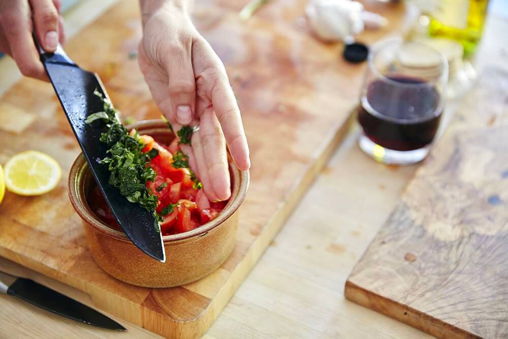 Chopped basil being added to tomato salad