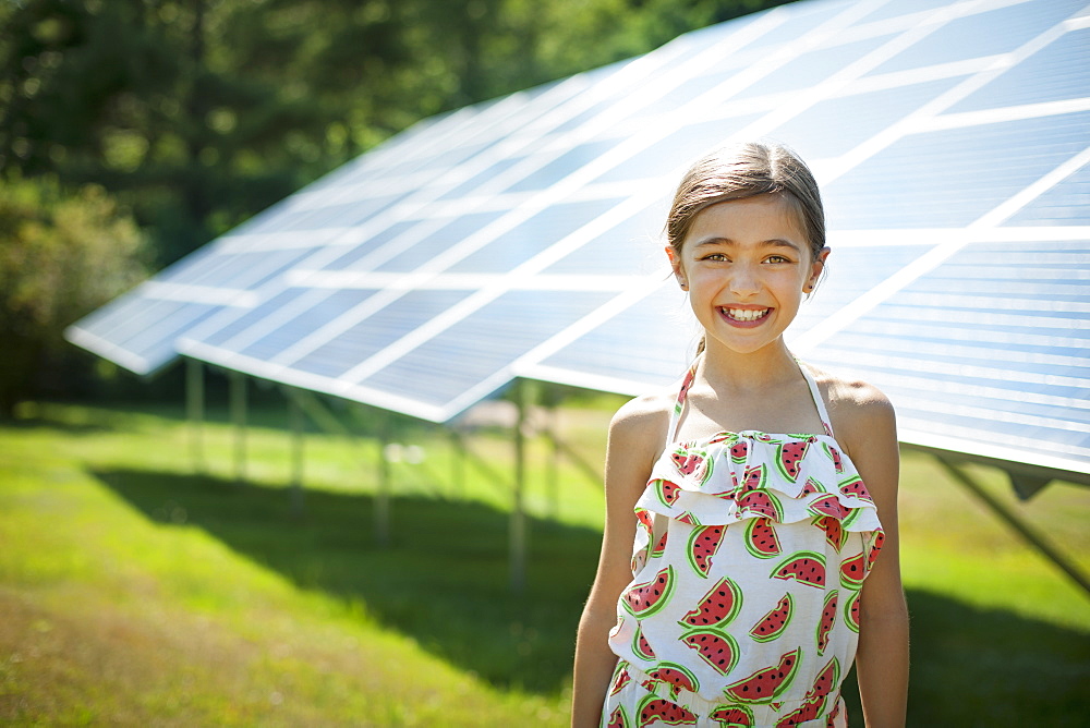 A child in the fresh open air on a sunny day, beside solar panels at a farm, New York state, USA