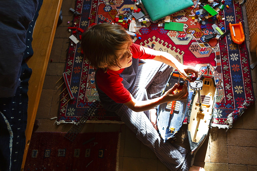 Overhead view of young boy in his room playing with his toys