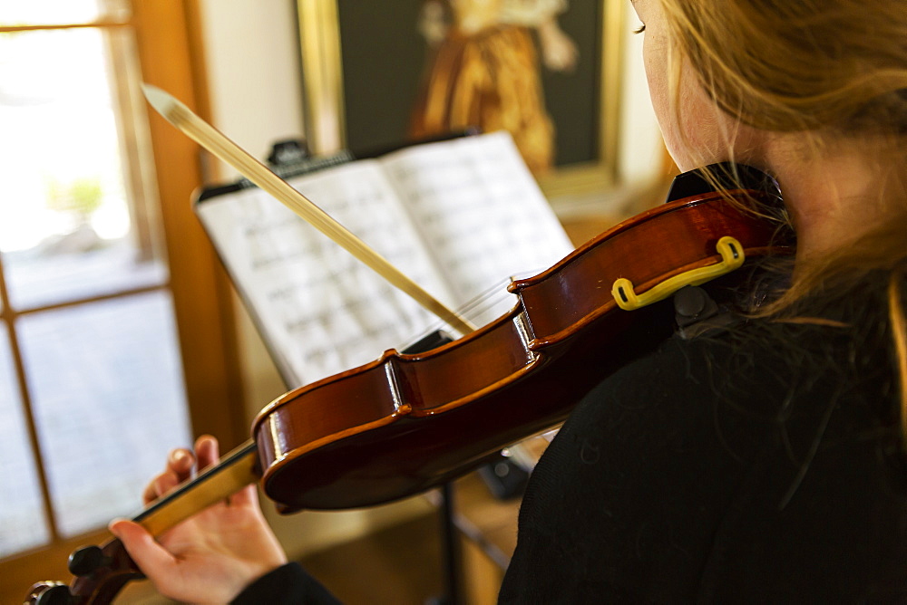 Teenage girl practicing violin at home