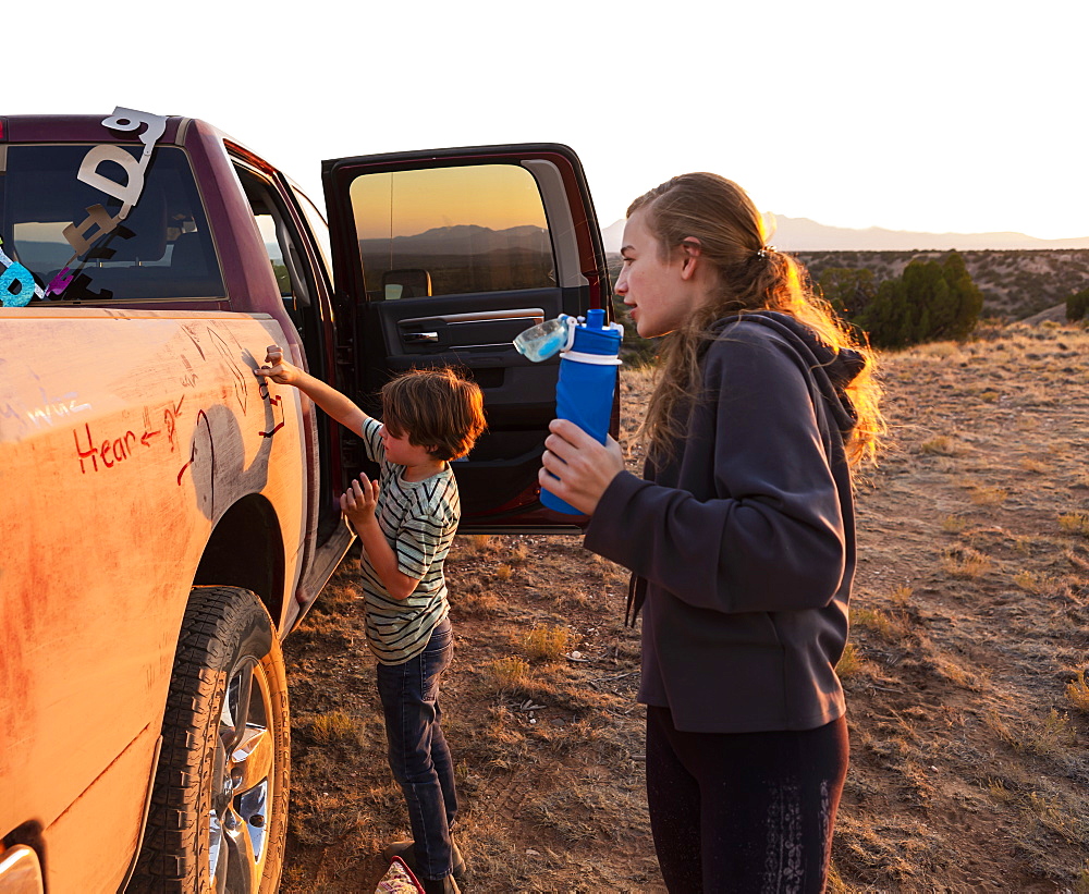 Two children painting the side of an old pickup truck