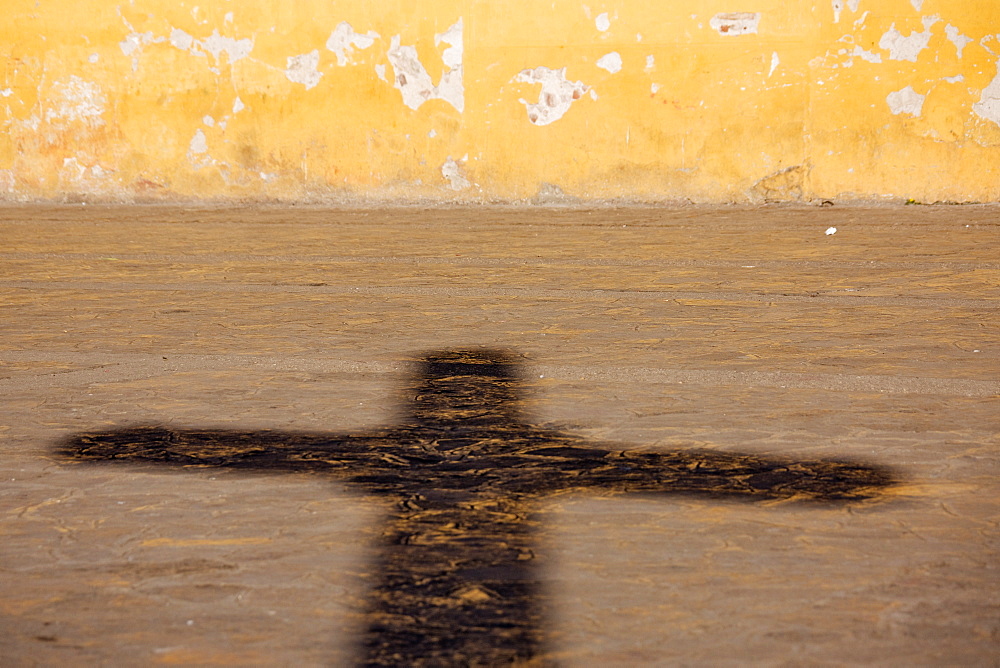 Shadow of a crucifix on a street pavement