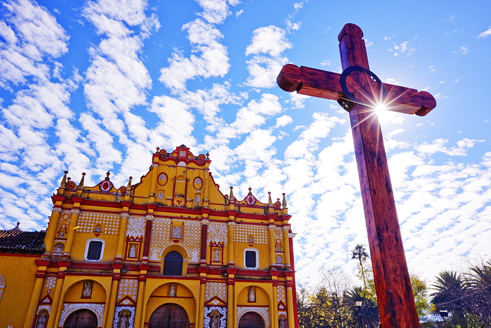 Crucifix in a courtyard in front of an ornate painted church