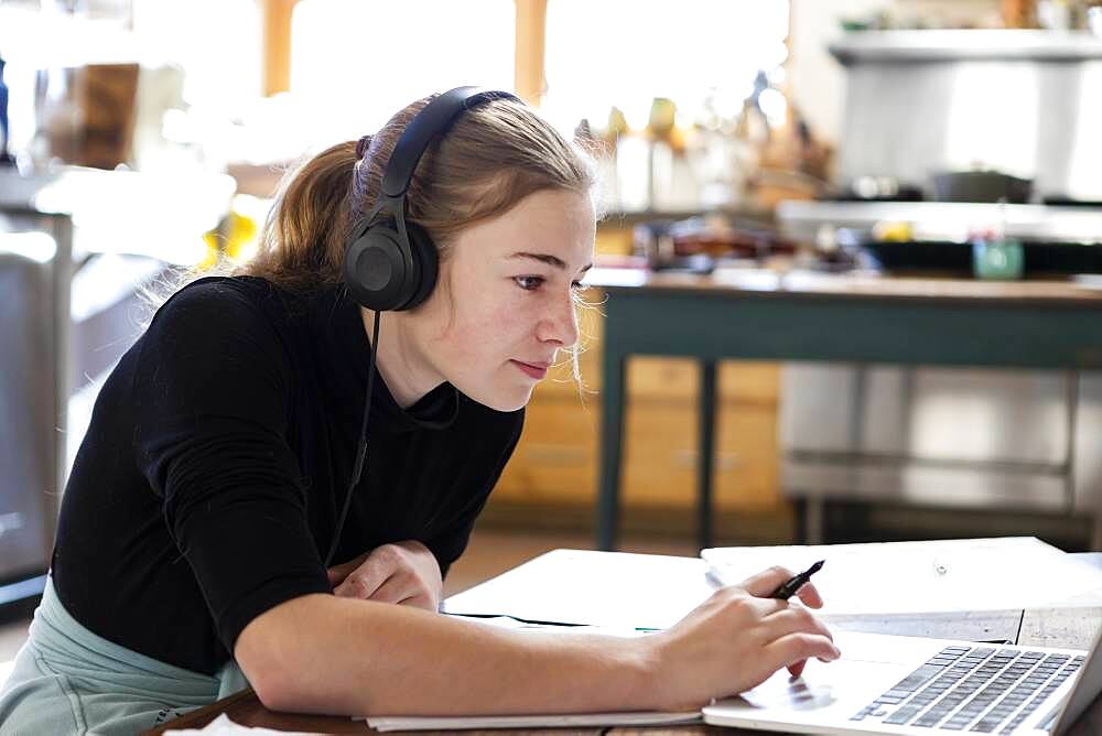 teenage girl wearing headphones, drawing on paper