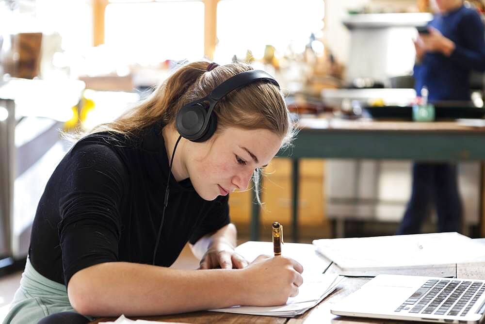 teenage girl wearing headphones, drawing on paper