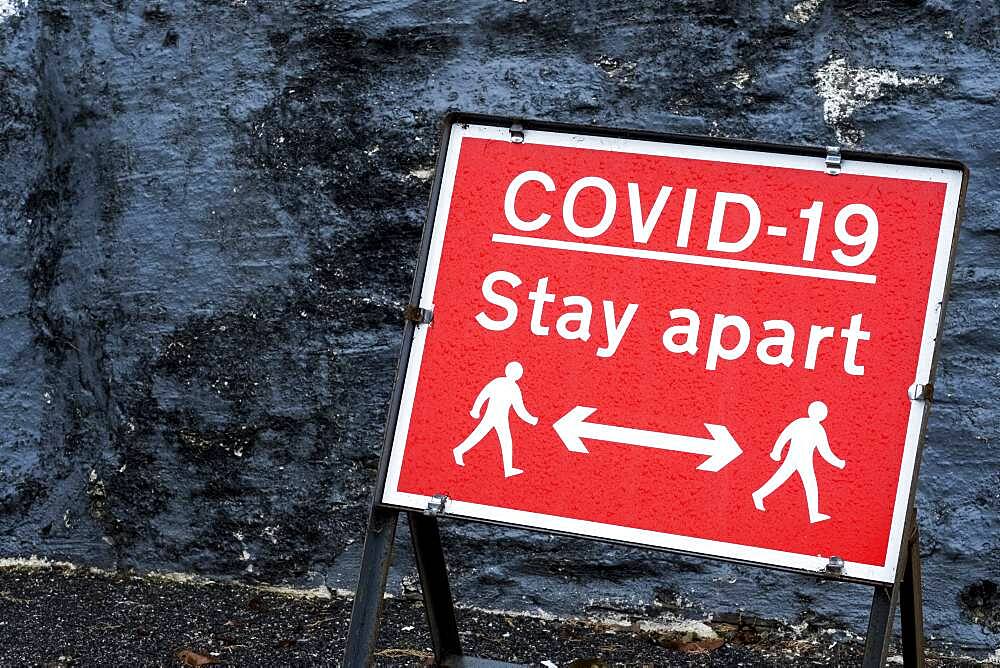 Close up of red and white Covid-19 distancing sign.