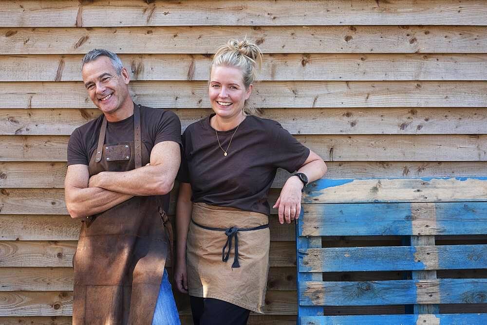 Man and woman in aprons, colleagues taking a break from work, laughing