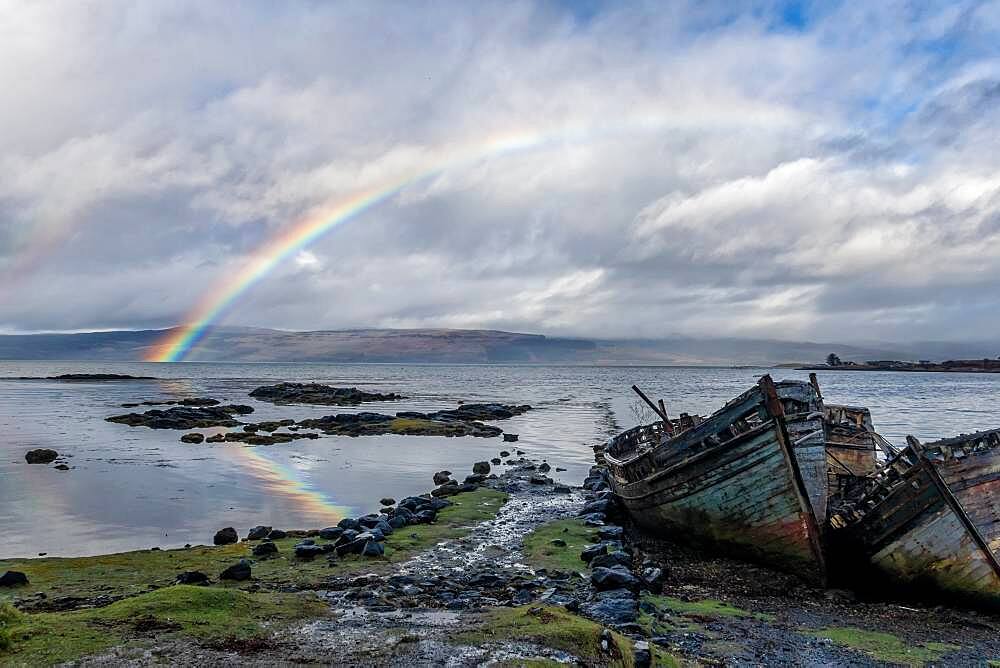 Rainbow and beached old wooden fishing boats on shore at Salen