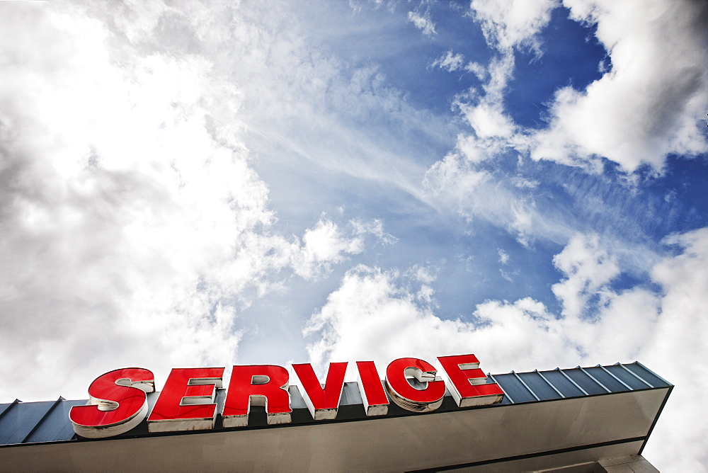 Auto service sign against partly cloudy blue sky viewed from below