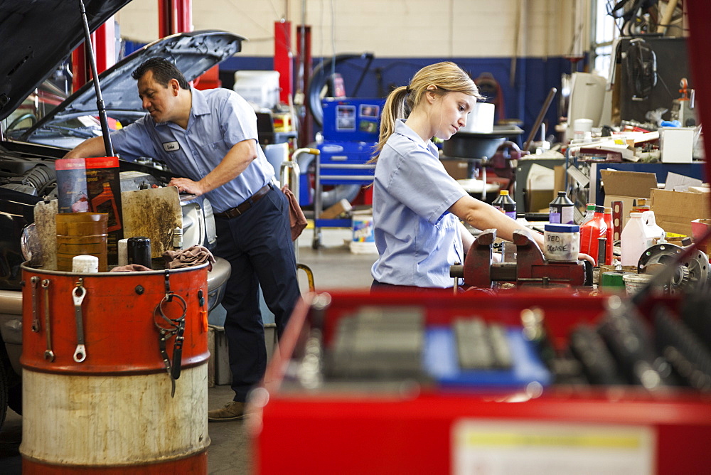 Caucasian female mechanic works on engine in auto repair shop