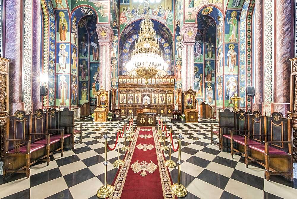 Serbian Orthodox church interior in Ljublijana, murals, painted pillars and walls, and chandelier.