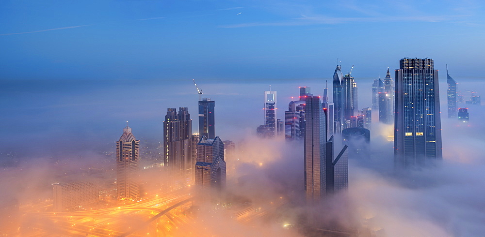 Cityscape with illuminated skyscrapers above the clouds in Dubai, United Arab Emirates at dusk, Dubai, United Arab Emirates