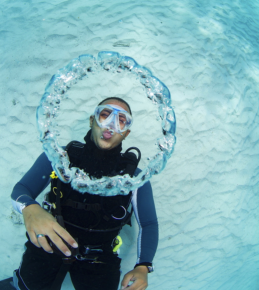 Scuba diver blowing bubble rings.  As the escaping air rises to surface, the decrease in pressure causes the rings of air to expand.