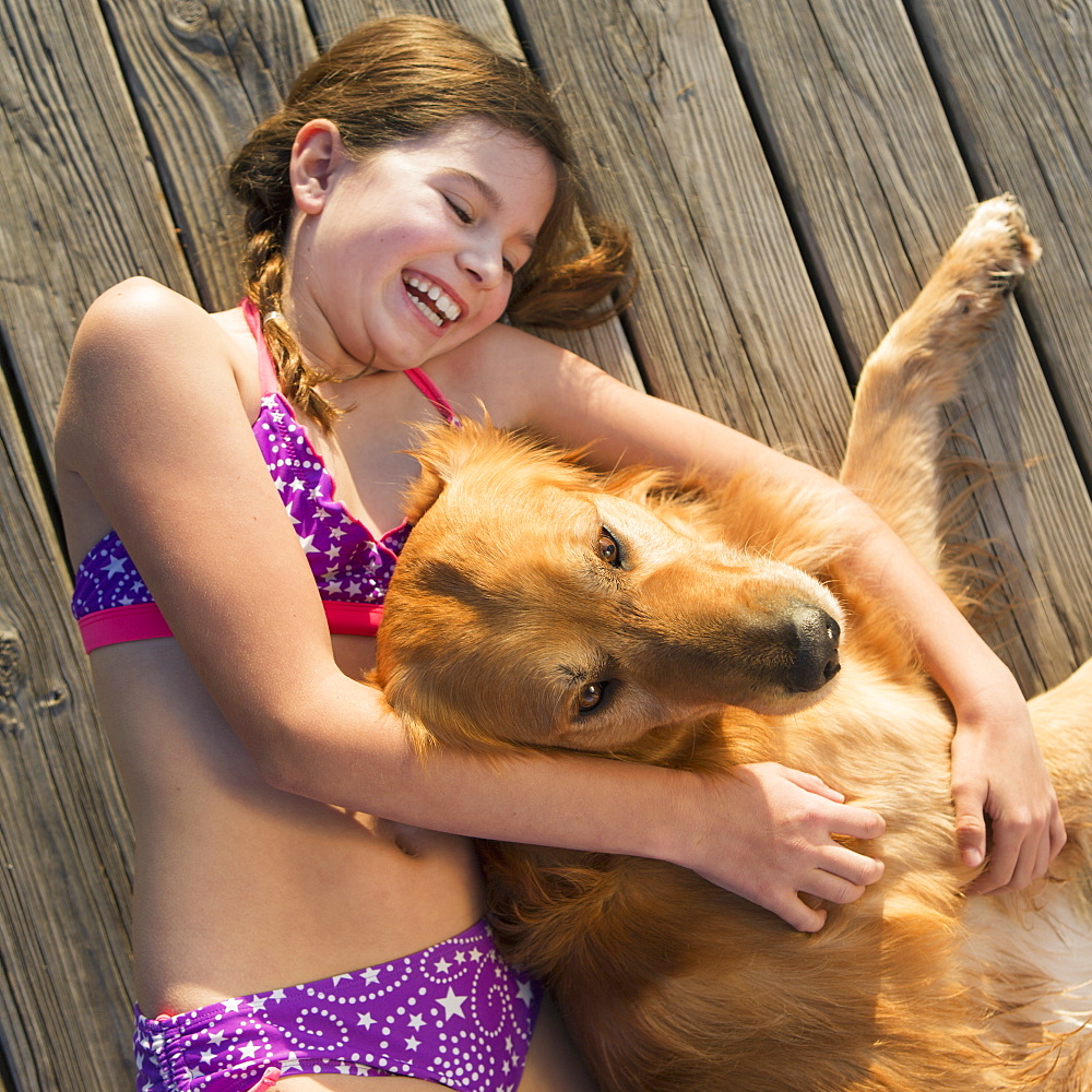 A girl in a bikini lying beside a golden retriever dog, viewed from above, Austin, Texas, USA