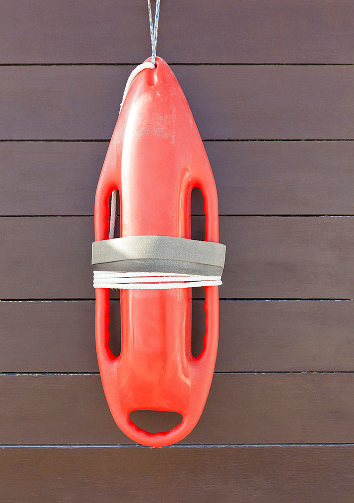 Orange lifeguard buoy, a safety float hanging on a wood wall